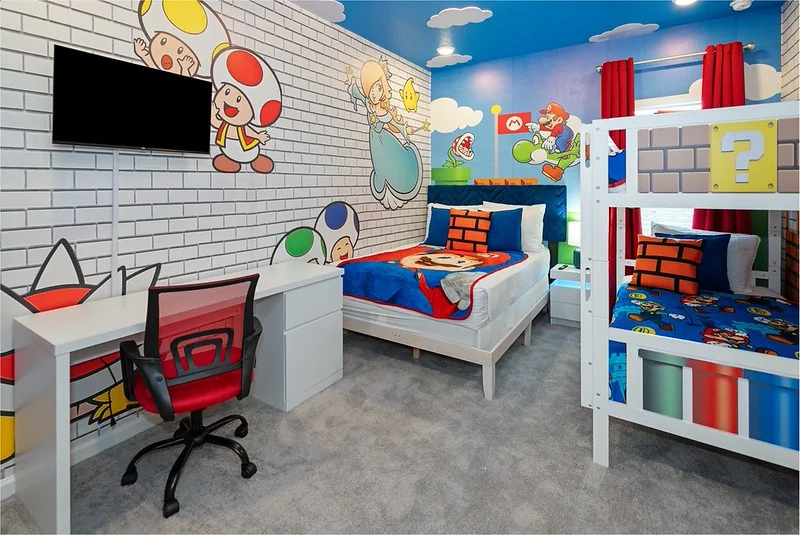 Game-themed kids bunk room with white bunk beds, a red desk chair and a painted brick mural in the Paradiso Grande Ebb Tide Lane home
